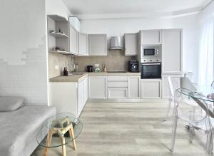 a white kitchen with white cabinets and a glass table at "Felicita" San Francesco lake view Relax Apartment in Lecco