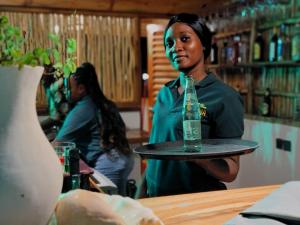 a woman holding a tray with a bottle on it at Aluna Beach House Nungwi in Nungwi +17 photos