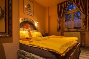 um quarto com uma cama com lençóis amarelos e uma janela em Hotel Villa Wirtshaus Köpenick em Hofgeismar