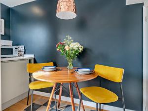 a dining room table with yellow chairs and a vase of flowers at 2 Bed in Helmsley oc-g0037 in Helmsley +10 photos