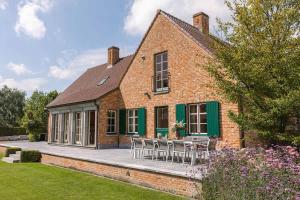 an external view of a brick house with tables and chairs at Casiola - Authentic Serene Vacation Hideaway with Pond in Harelbeke