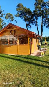 a small yellow building with a porch in the grass at Sternik Dom gościnny in Niechorze