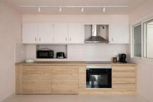 a kitchen with white cabinets and a black appliance at Winahost La Llar del Mar in San Pol de Mar