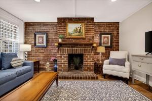 a living room with a brick fireplace with a couch and a chair at Troup Square Manor Garden by Lucky Savannah in Savannah