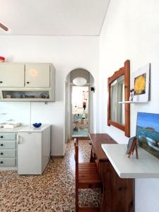 a kitchen with white cabinets and a table and a chair at Dandelion Paros Apartments IV in Kóstos