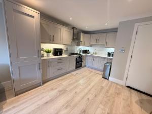 a kitchen with white cabinets and a wooden floor at Coastal Charm in Dublin