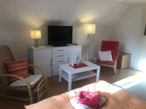ein Wohnzimmer mit Fernseher und zwei Sesseln in der Unterkunft Glück in Benrath in Düsseldorf