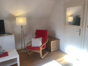 ein roter Stuhl mit einem weißen Kissen in einem Zimmer in der Unterkunft Glück in Benrath in Düsseldorf