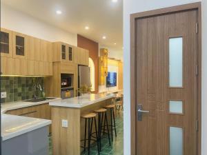 a kitchen with wooden cabinets and a bar with stools at Tata Van in Ấp Sung Xuân +12 photos
