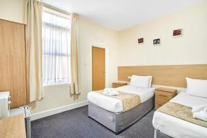 a hotel room with two beds and a window at Britannia Inn Hotel in Ilford
