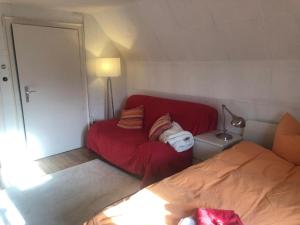 ein kleines Zimmer mit einer roten Couch und einem Bett in der Unterkunft Glück in Benrath in Düsseldorf