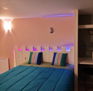 a bedroom with a blue bed with purple lighting at Les chambres de Noëlla in LʼAiguillon-sur-Vie
