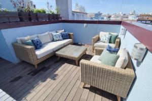 a patio with wicker chairs and couches on a balcony at Apartamentos Libertad 24 in Madrid