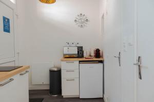 a kitchen with white cabinets and a white refrigerator at AppartUnique - Chez Layette - Hypercentre & Design Moderne in Vichy