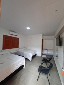 a room with two beds and a chair in it at Cachoeira e Pousada dos Pássaros in Presidente Figueiredo