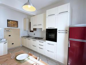 a kitchen with white cabinets and a red refrigerator at Casa Marlù - ArgonautiVacanze in Porto Azzurro