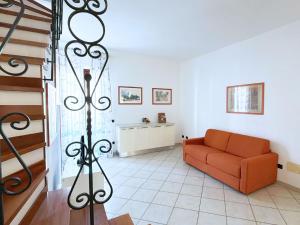 a living room with a orange couch and a staircase at Casa Marlù - ArgonautiVacanze in Porto Azzurro