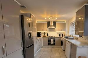 a kitchen with white cabinets and a refrigerator at Your Versatile Luxury - Space for All- Sleeps 10 in Bedford +11 photos