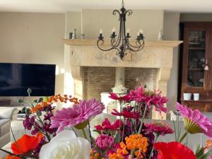 a bunch of flowers in a living room with a fireplace at Vakantiehuis Vloethem in Zedelgem