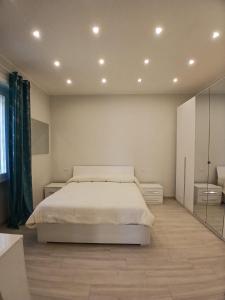 a white bedroom with a bed and a mirror at Grazia Nest in Ciampino
