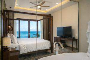 a bedroom with a bed and a tv and a mirror at Gardens Hill Resort & Spa in Beau Vallon