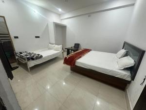a bedroom with two beds and a table in it at Hotel Sharda Palace in Deoghar +17 photos