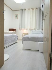 a white bedroom with two beds and a window at K Hubhouse - Taereung stn 5min walk#villa 4pax in Seoul