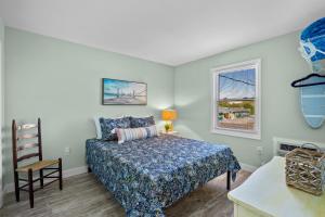 a bedroom with a bed and a chair and a window at Vitamin Sea Suites 4 in Carolina Beach
