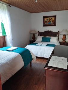 a bedroom with two beds and a table with a table at Alojamiento Rural San Antonio in Ubaté
