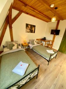 two beds in a room with wooden ceilings at Młyn Wielisław Agroturystyka i Restauracja in Sędziszowa
