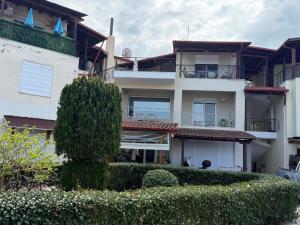 a large white building with bushes in front of it at Tropical Apartment Hanioti in Hanioti