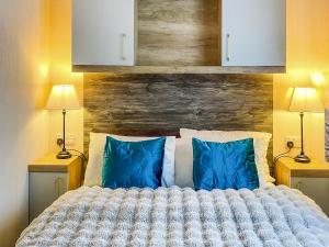 a bedroom with a bed with blue pillows and two lamps at Bordeaux in Heysham