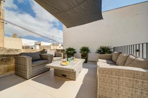 a patio with wicker chairs and tables on a balcony at Zaffir Retreat in Żebbuġ