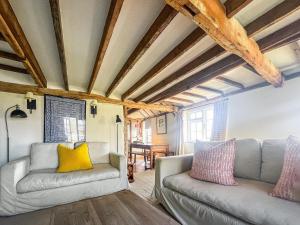 a living room with two couches and wooden ceilings at Prospect Cottage in Wittersham