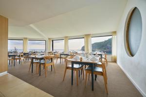 a dining room with tables and chairs and windows at Caloura Hotel Resort in Caloura