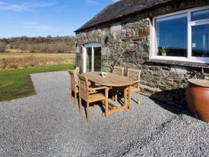 a wooden table and chairs in front of a stone building at Coelard The Barn - Uk50538 in Appin