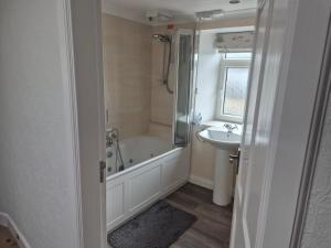 a bathroom with a bath tub and a sink at Three Trees Cottage in Lochmaben +95 photos