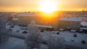 a building with the sun setting in the background at Postmaster Hotel in Rovaniemi
