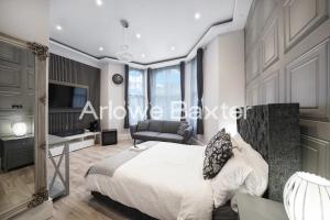 a bedroom with a bed and a chair and a television at Hackney Suites - En-suite rooms & amenities in London