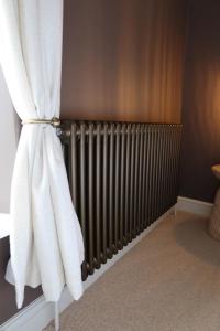 a radiator in a room with a white curtain at Plum Cottage in Cottesmore