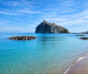 a beach with a castle on top of an island at Beach House Ischia - Seafront & Aragonese Castle View - in Ischia Town
