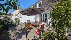 a patio with a table and chairs and an umbrella at am-hoeben in Fehmarn +15 photos