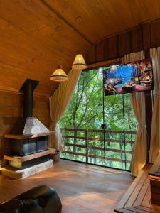 a living room with a fireplace and a large window at Chalé Belluno in Casca