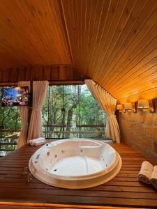 a large bath tub in a room with a large window at Chalé Belluno in Casca +16 photos