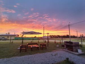 a sunset with a picnic table and an umbrella at Cabañas - Raíces de la Sierra in Balcarce +2 photos