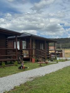 a log cabin with a dog laying in front of it at Cabañas - Raíces de la Sierra in Balcarce
