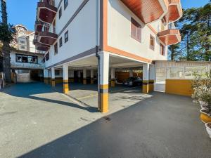 a building with a parking lot with a car in it at Pousada Vilage Inn Campos do Jordão in Campos do Jordão