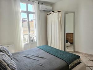 a bedroom with a bed and a large window at L'Authentique Centre-Ville - Perpignan in Perpignan