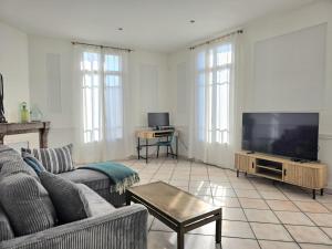 a living room with a couch and a flat screen tv at L'Authentique Centre-Ville - Perpignan in Perpignan