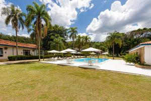 a swimming pool with chairs and umbrellas next to a house at Fazenda Santanna Hotel in Amparo